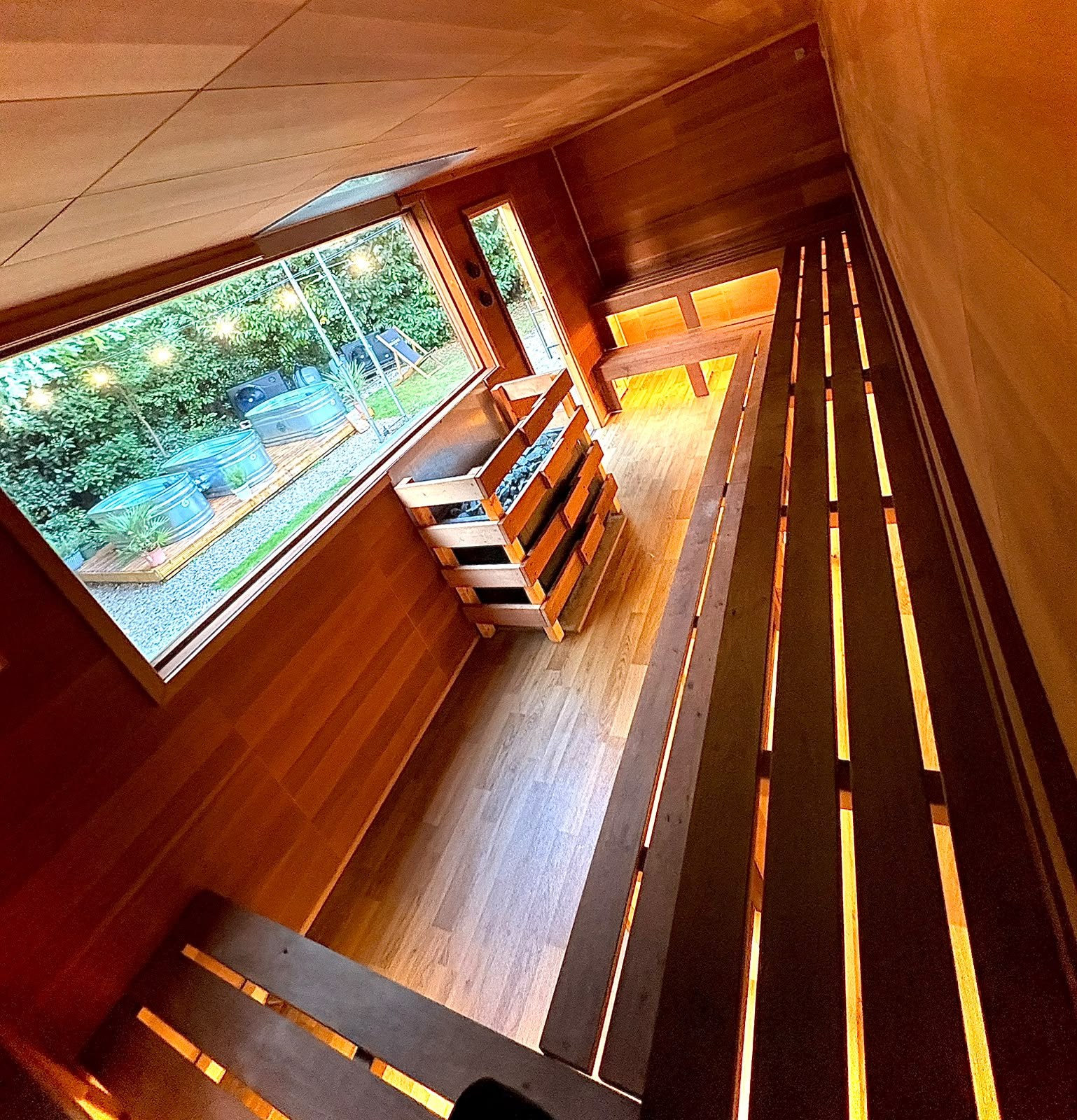 Timber sauna benches beside a window overlooking greenery